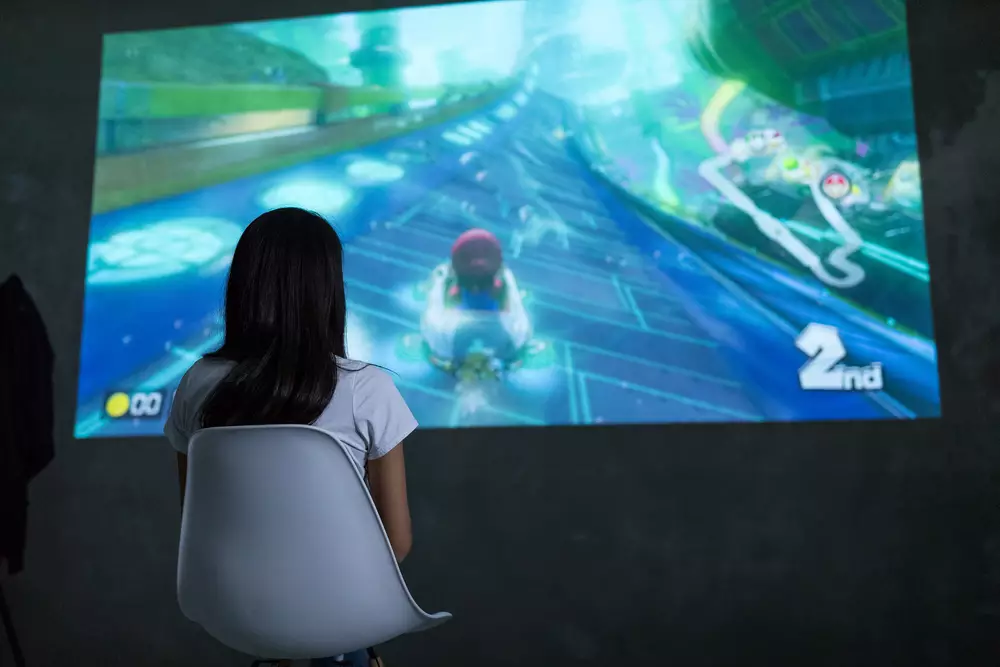 Woman playing Nintendo Switch console over big screen